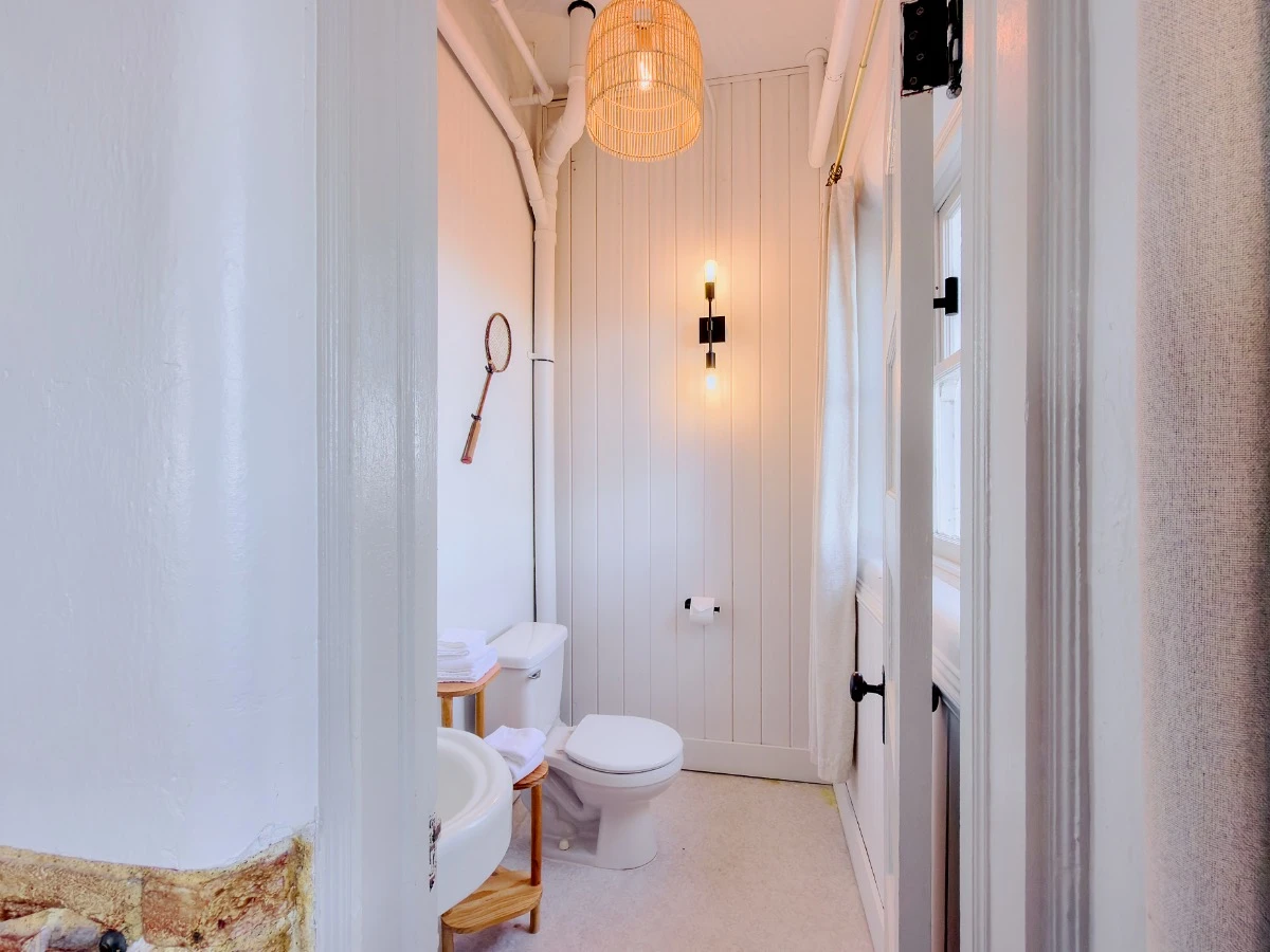 Well-lit bathroom in Room 113 at Hot Lake Springs Resort with toilet and window visible.