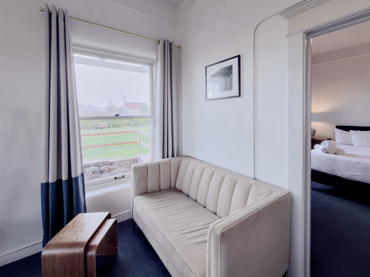 Grey sofa and wood coffee table seating area by window in Room 113 at Hot Lake Springs Resort, doorway to second bedroom in background.