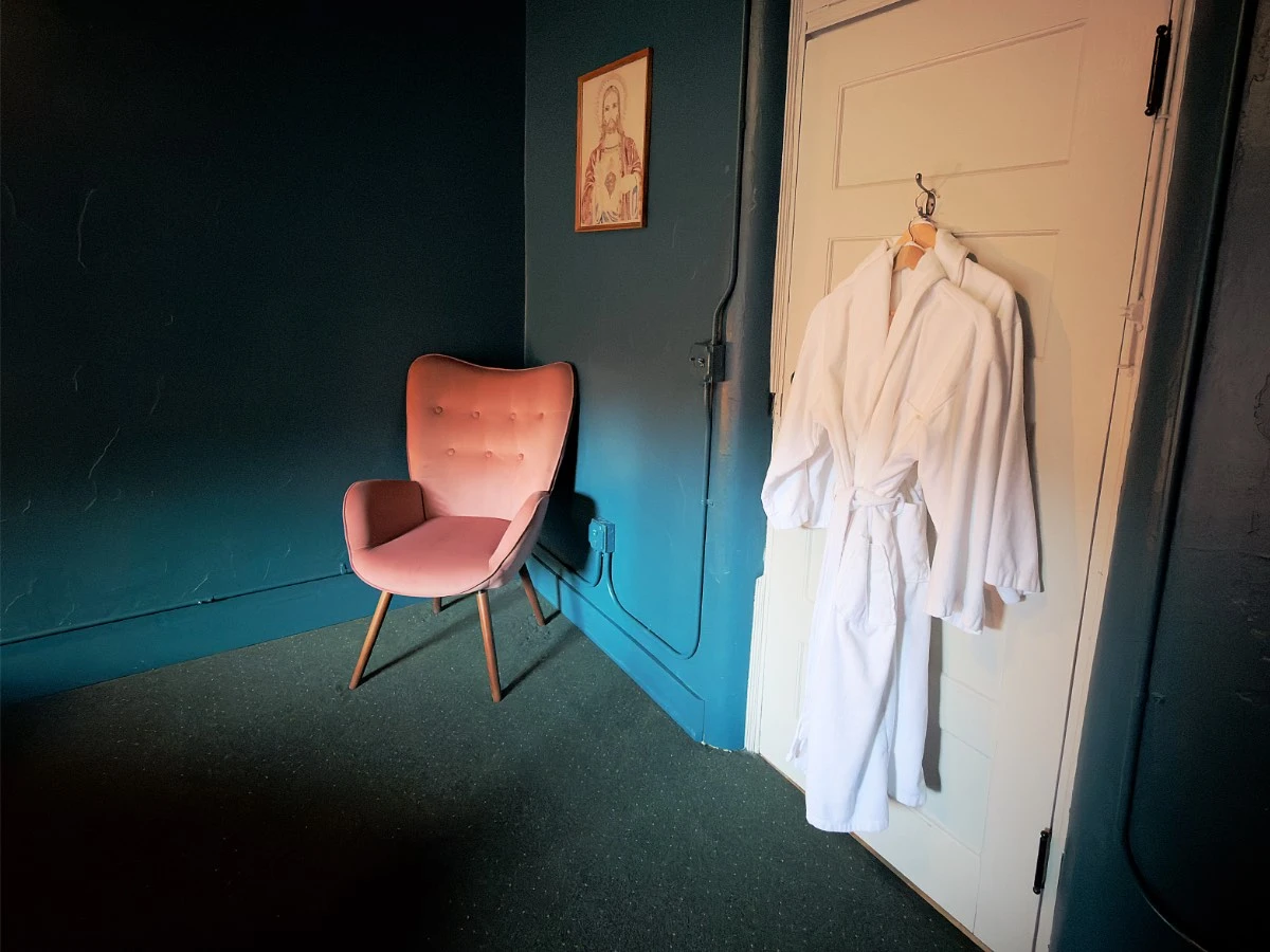 Orange chair for sitting and relaxing in Room 206 at Hot Lake Springs Resort, bath robes hanging from closed door to the right.