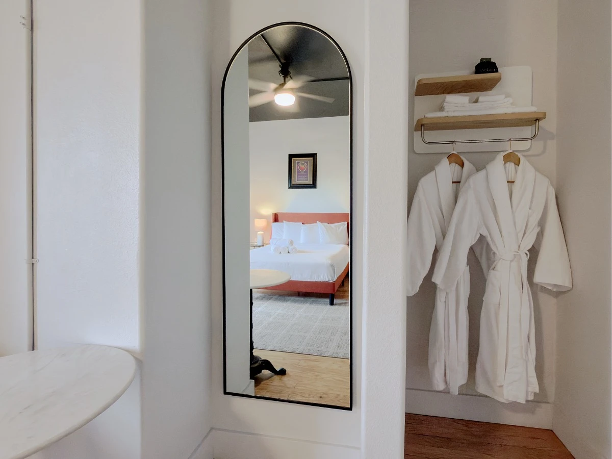 Mirror reflecting the bed in Room 207 at Hot Lake Springs Resort, white bath robes hanging to the right of the mirror.