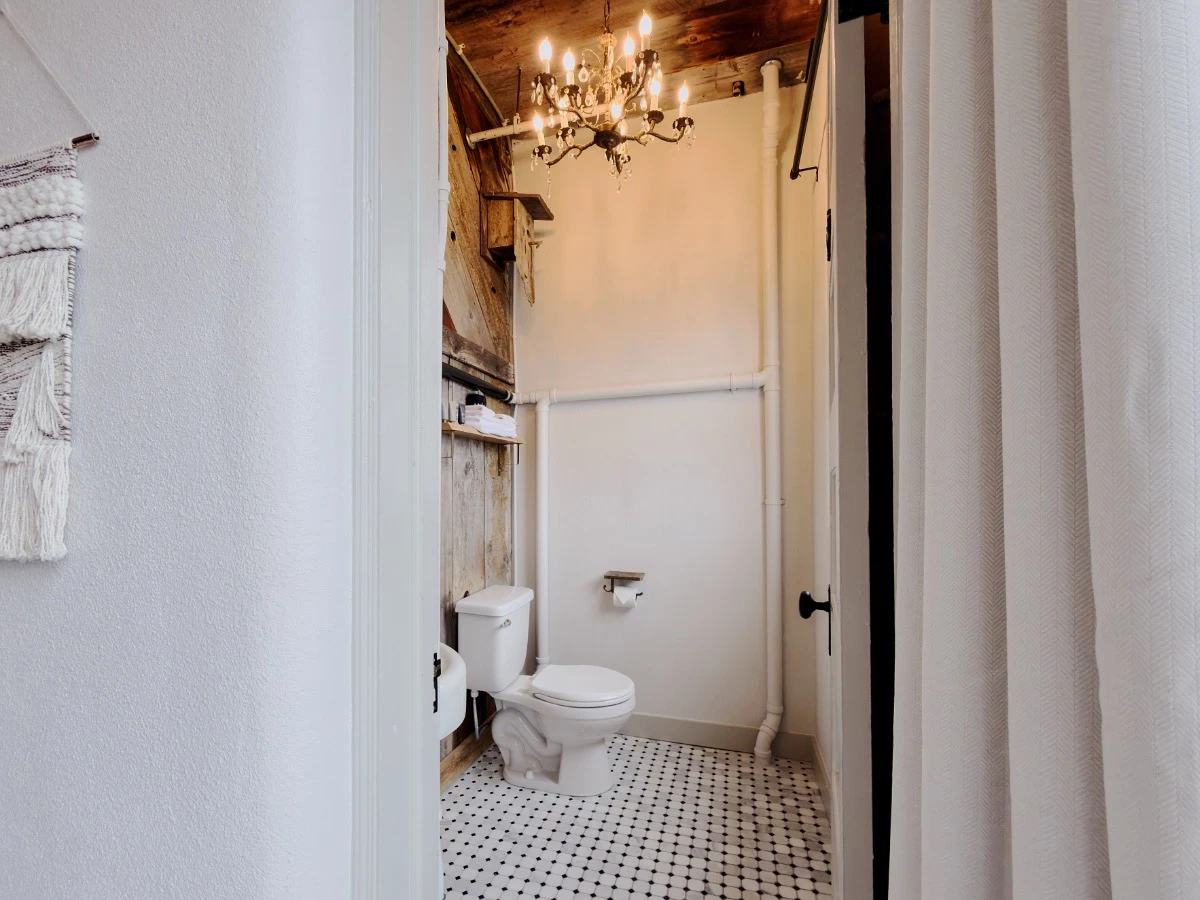 Bathroom in Room 213 at Hot Lake Springs Resort with toilet visible, rustic wood walls on left, tile bathroom floor.
