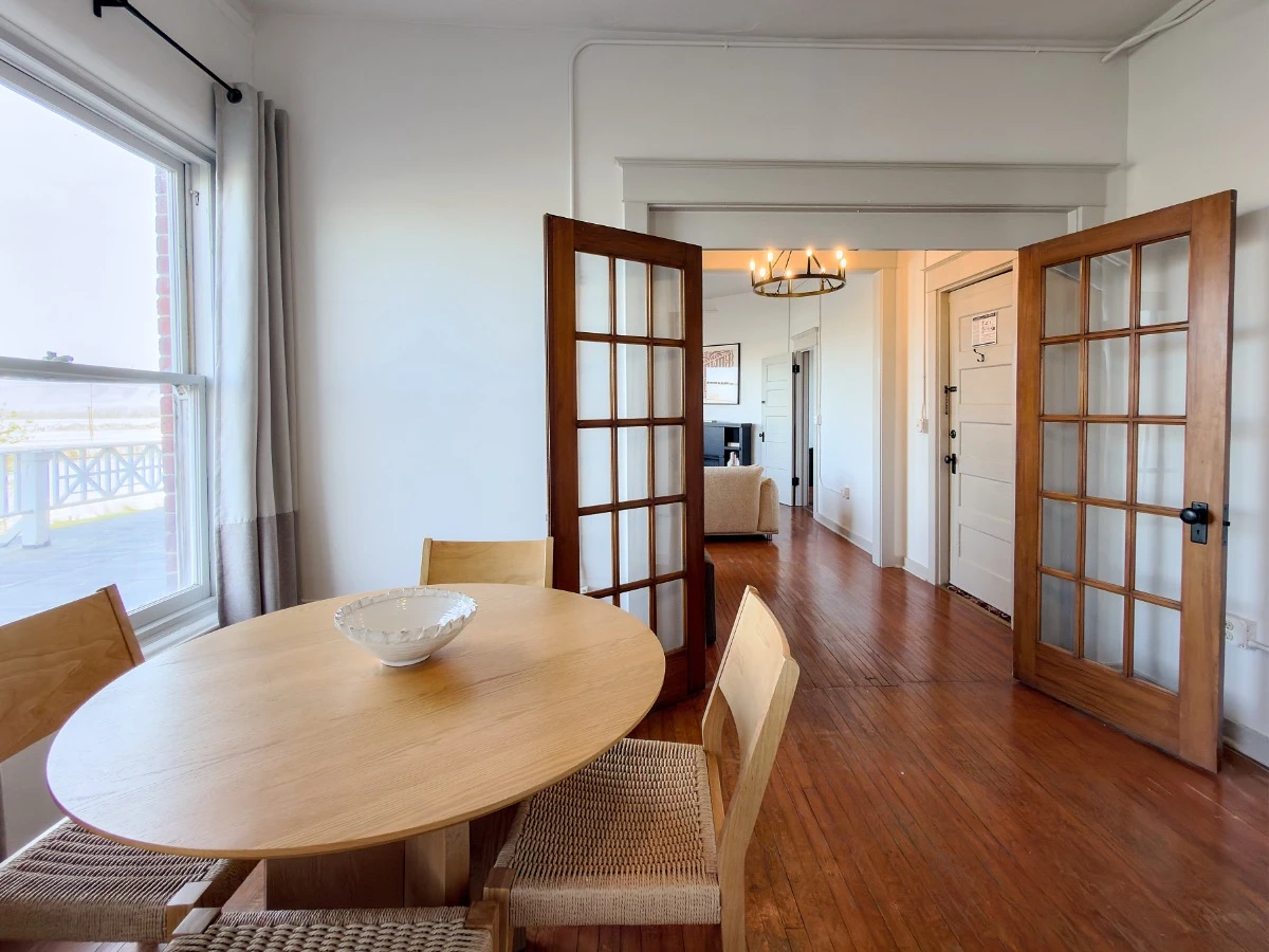 Kitchen in Room 231 at Hot Lake Springs Resort looking toward living room, partial view of table and chairs in left foreground, open French doors show living room in background.