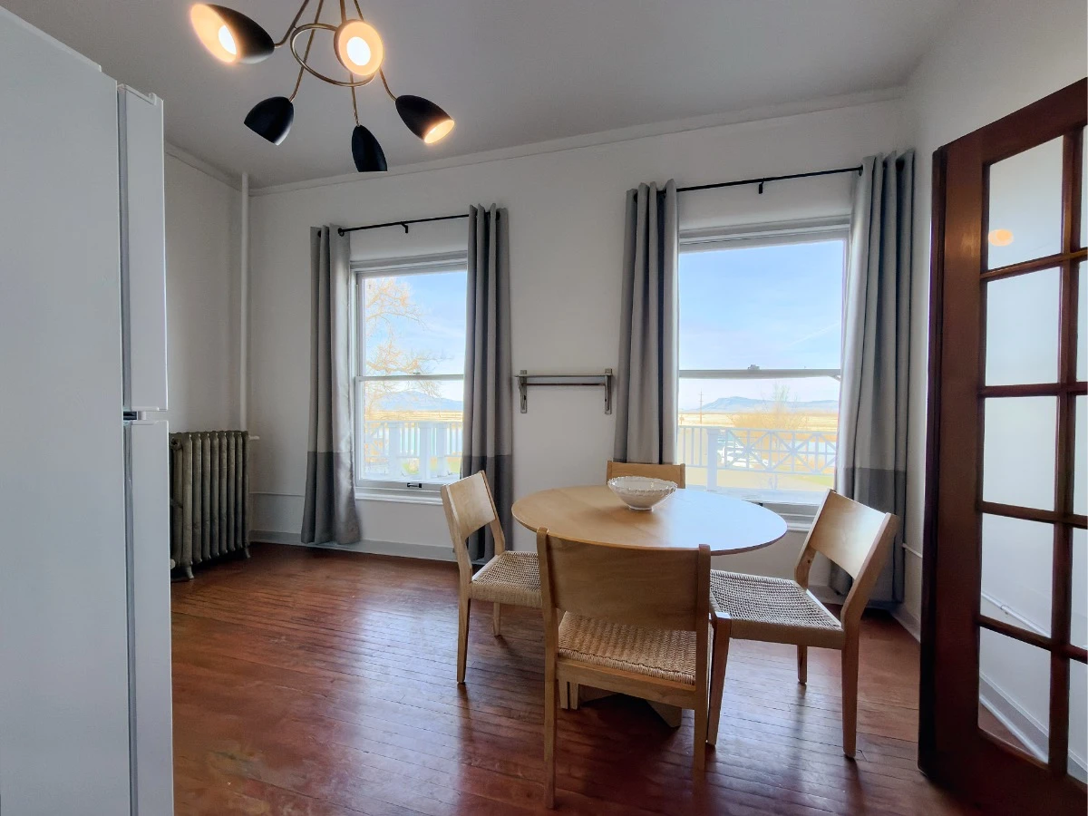 Wood round kitchen table by windows with four chairs around table in Room 231 at Hot Lake Springs Resort, wood floors.
