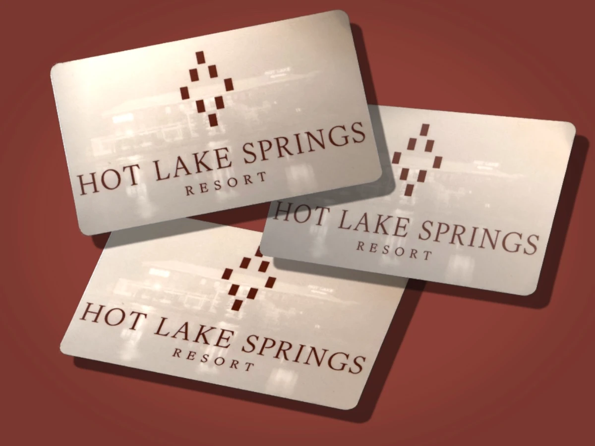 Three white Hot Lake Springs Resort gift cards with logo on red background, appearing to float or fall.