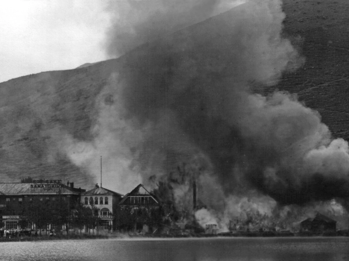 1934 fire at Hot Lake Springs Resort, smoke billowing from burning wooden sections, viewed from across Hot Lake.