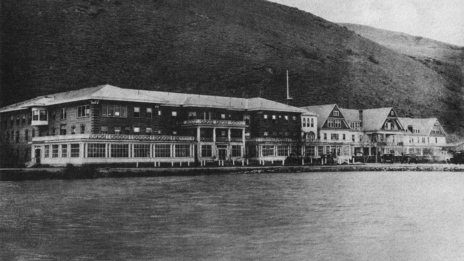Historic black-and-white view of Hot Lake Springs Resort front pre-1934 fire, showing lake in foreground and original wooden buildings on west side still intact.