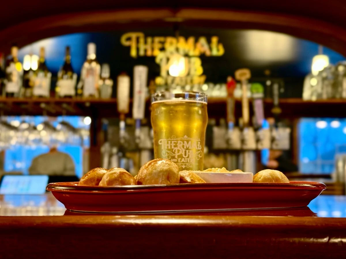 Pretzel bites and cold beer on bar top in Thermal Pub & Eatery, mirror with Thermal Pub logo in background.