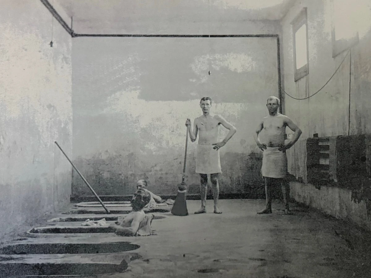 Early 20th-century indoor soaking tubs at Hot Lake Springs Resort, two men bathing in floor-level tubs and two others standing in towels.