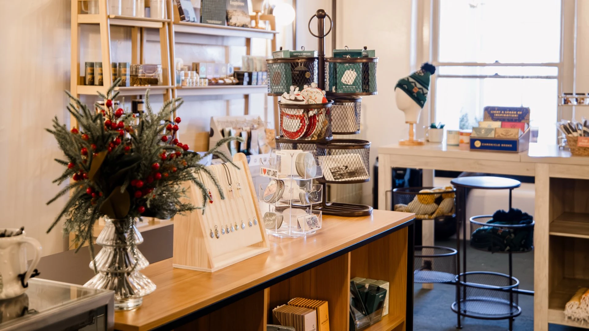Interior of Gift Shop at Hot Lake Springs Resort, showing counter display, table with stickers, hats, jewelry, lip balm, and assorted keepsakes.