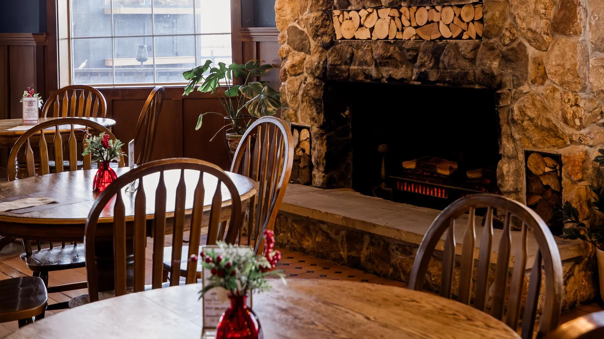 Rustic wood tables in foreground with stone fireplace in background at Thermal Pub & Eatery, Hot Lake Springs Resort.