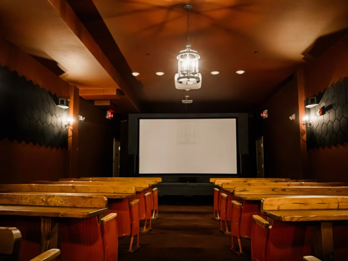 Empty 60-seat theater at Hot Lake Springs Resort, cozy rows with bar tables in front for placing food and drinks.