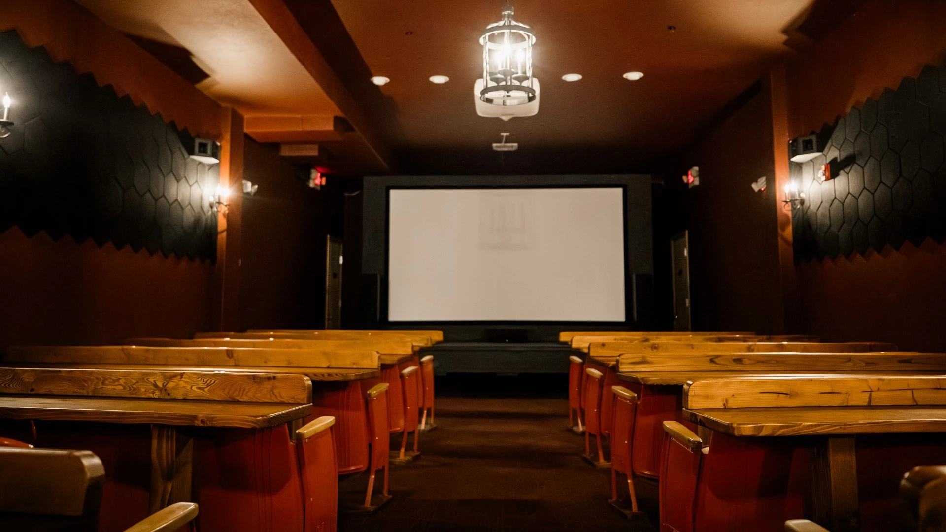Empty 60-seat theater at Hot Lake Springs Resort, cozy rows with bar tables in front for placing food and drinks.